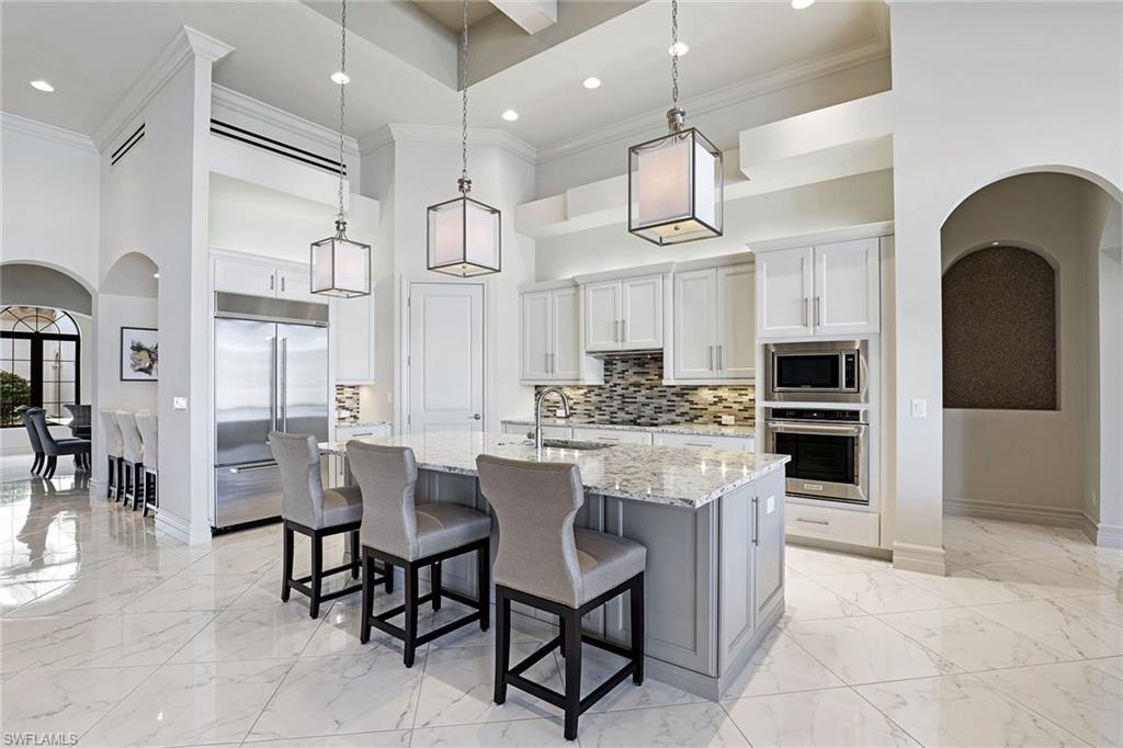 16459 Seneca Way Naples, FL 34110 - Photo 5 of 50 a kitchen with stainless steel appliances kitchen island granite countertop a table chairs and a refrigerator