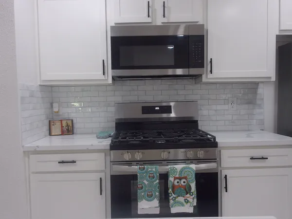 a kitchen with stainless steel appliances granite countertop white cabinets stove top oven and microwave