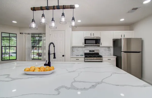 a kitchen with stainless steel appliances kitchen island granite countertop a refrigerator a stove a microwave oven a sink with a dining table and chairs