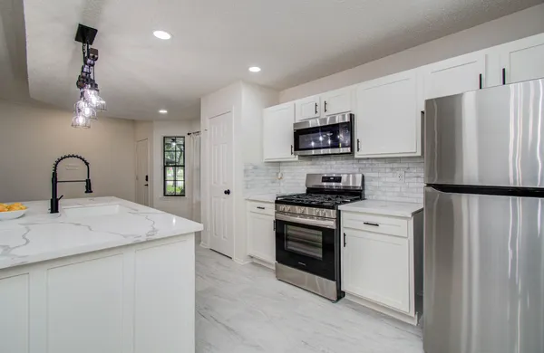 a kitchen with stainless steel appliances granite countertop a sink stove and refrigerator