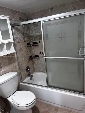 a white toilet sitting next to a bath tub and a shower