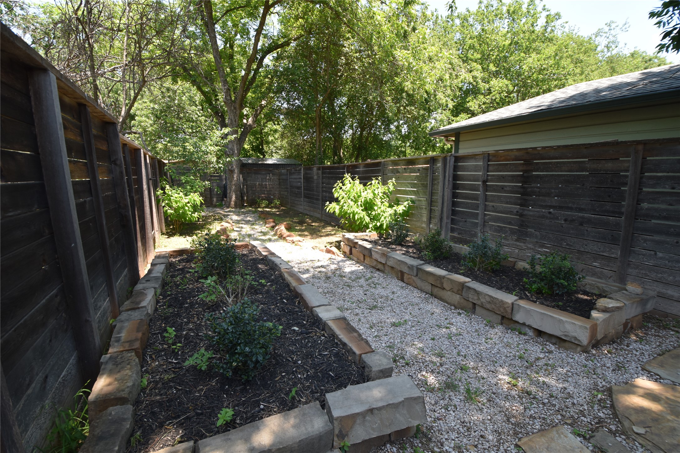 2012 Payne Avenue, Unit A Austin, TX 78757 - Photo 30 of 33 Enclosed outdoor space featuring wood fencing, gravel pathways, and stone-edged garden beds