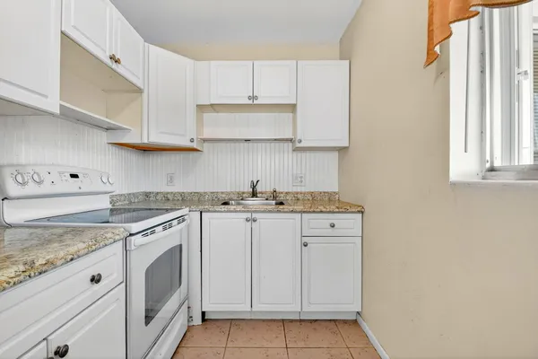 a kitchen with granite countertop white cabinets and white appliances