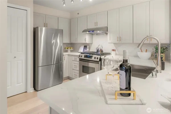 a kitchen with stainless steel appliances granite countertop a sink a stove and a refrigerator