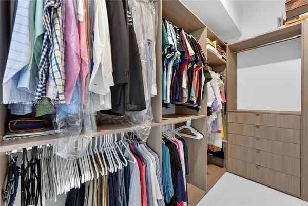 a view of walk in closet with clothes and shoes