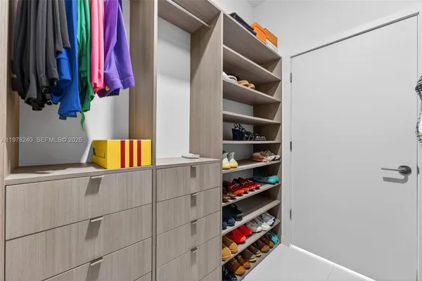 a view of walk in closet with clothes and shoes