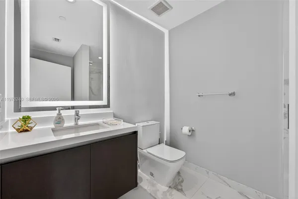 a bathroom with a granite countertop sink a toilet and a mirror