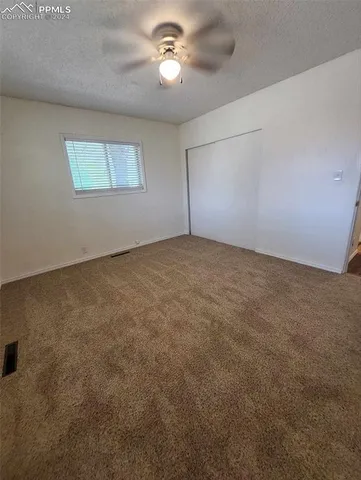 an empty room with a chandelier fan and windows