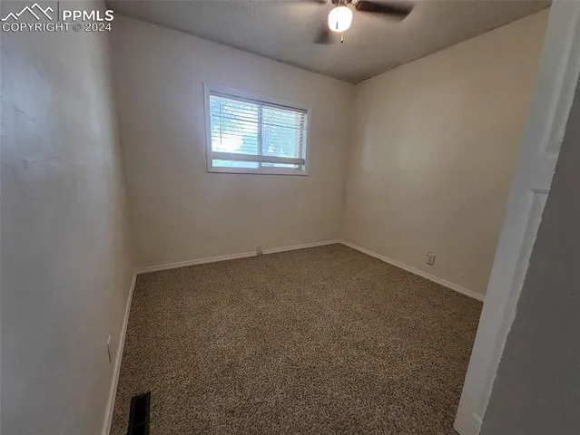 an empty room with a chandelier fan and windows