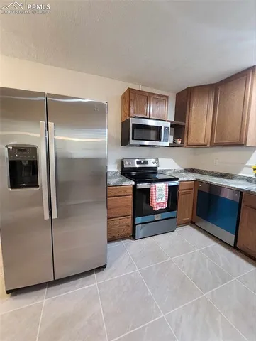 a kitchen with stainless steel appliances granite countertop a stove a sink and a refrigerator