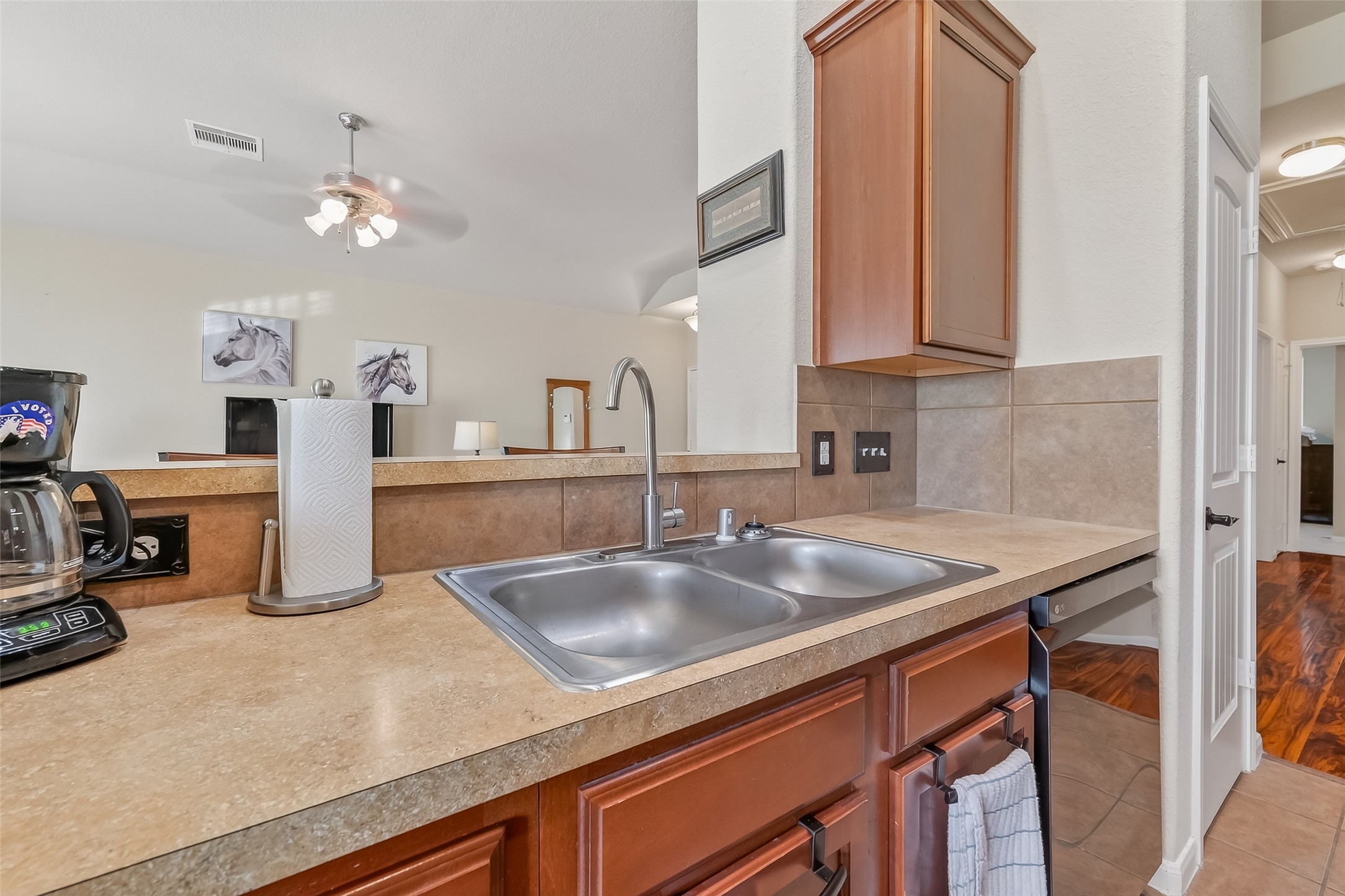 22454 Toronado Ridge Lane Porter, TX 77365 - Photo 13 of 33 This kitchen features a double sink with a modern faucet, wooden cabinets, and a tiled backsplash. The area opens to a living space .