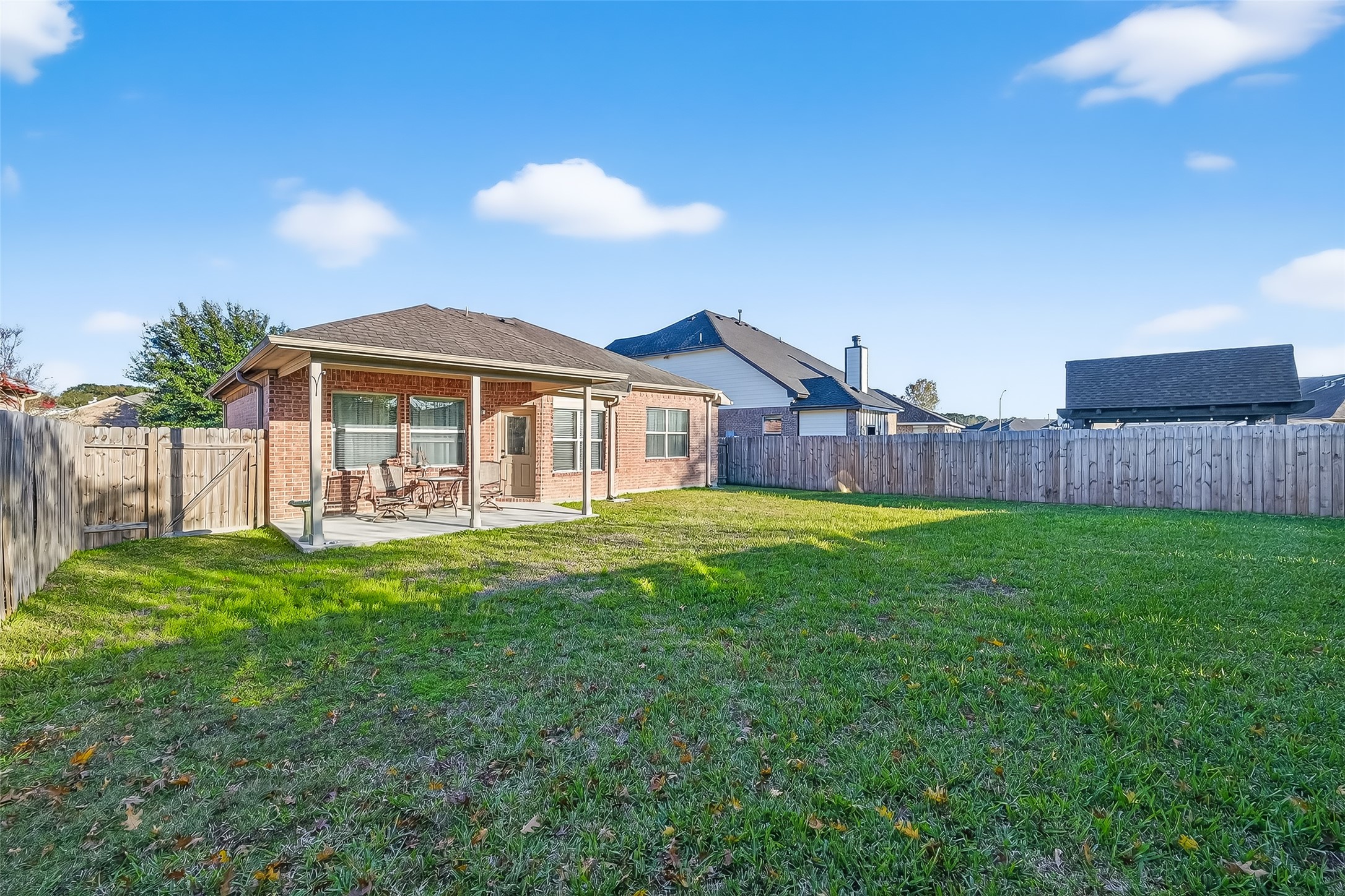 22454 Toronado Ridge Lane Porter, TX 77365 - Photo 29 of 33 Spacious backyard featuring a covered patio perfect for outdoor relaxation. The area is enclosed by a wooden fence, providing privacy and security. Ideal for families or entertaining guests.