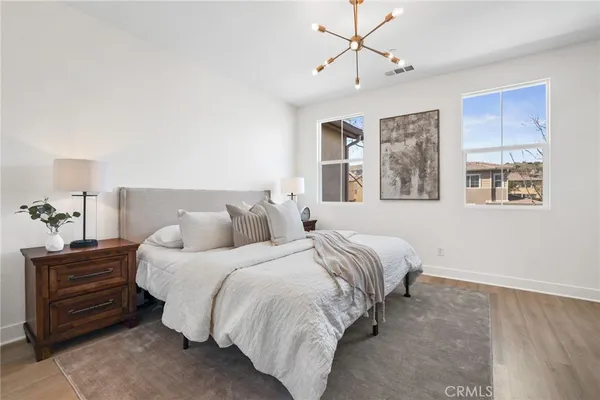 a bedroom with a bed a mirror and a lamp on dresser