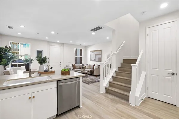 a room with lots of white furniture and wooden floor
