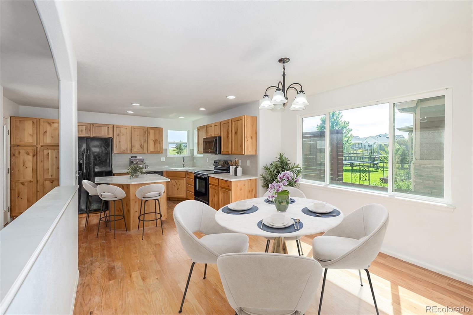 2188 Grain Bin Windsor, CO 80550 - Photo 6 of 30 a dining room with wooden floor a chandelier a glass table and chairs