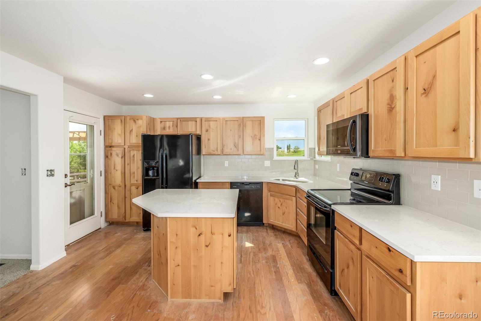 2188 Grain Bin Windsor, CO 80550 - Photo 9 of 30 a kitchen with stainless steel appliances granite countertop a refrigerator a stove top oven a sink dishwasher and wooden cabinets with wooden floor