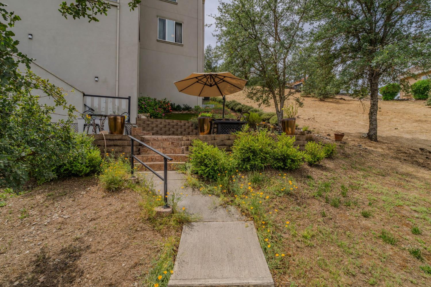 6066 Bluff View Road Copperopolis, CA 95228 - Photo 79 of 96 a backyard of a house with table and chairs under an umbrella