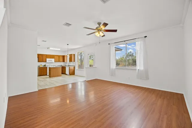 a view of an empty room with window and wooden floor