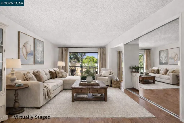 a view of an empty room with wooden floor and a kitchen