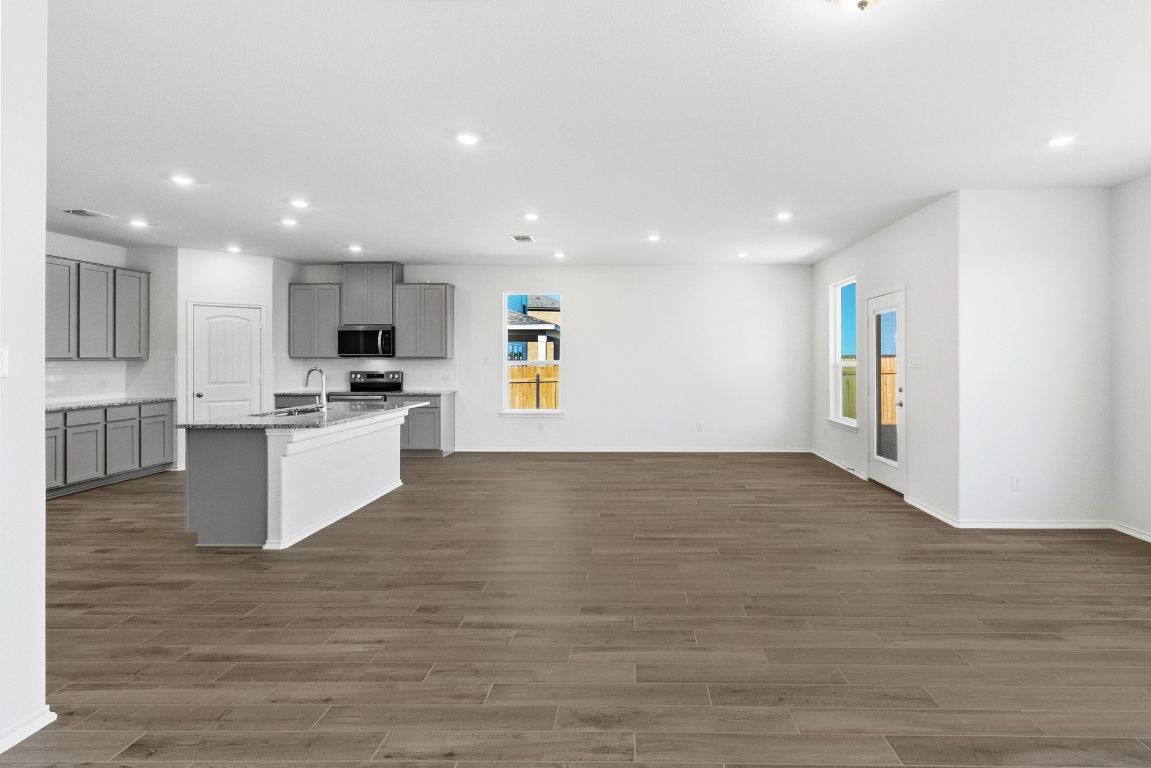 Undisclosed Address Manor, TX 78653 - Photo 5 of 31 a view of kitchen with kitchen island granite countertop a stove top oven a sink and a refrigerator
