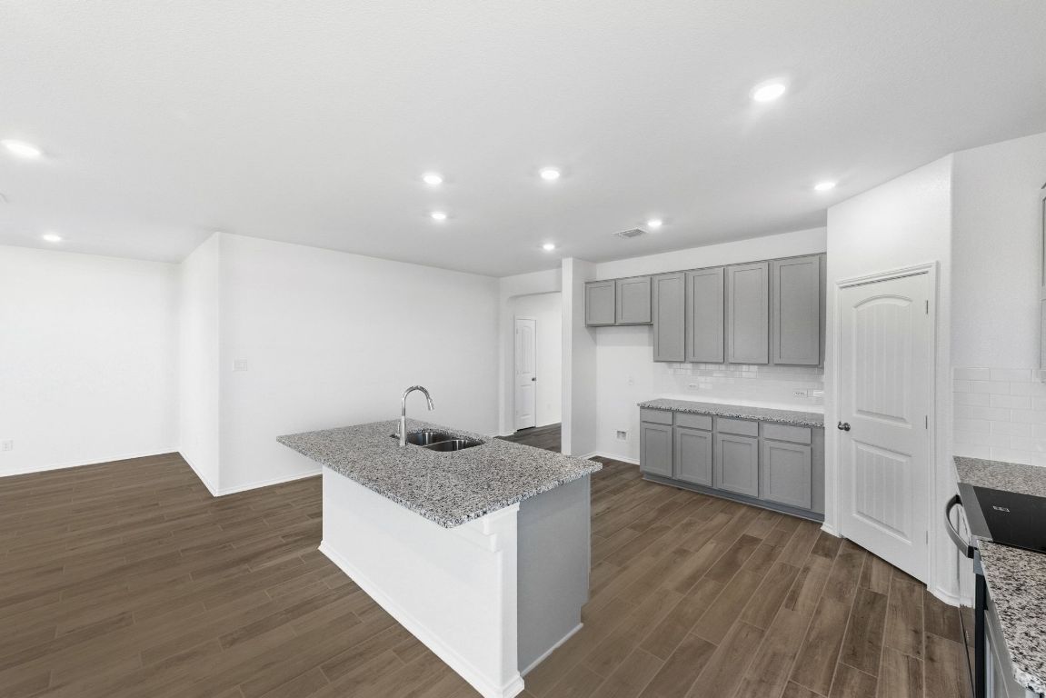 Undisclosed Address Manor, TX 78653 - Photo 10 of 31 a kitchen with stainless steel appliances granite countertop a sink dishwasher a stove and a refrigerator with wooden floor