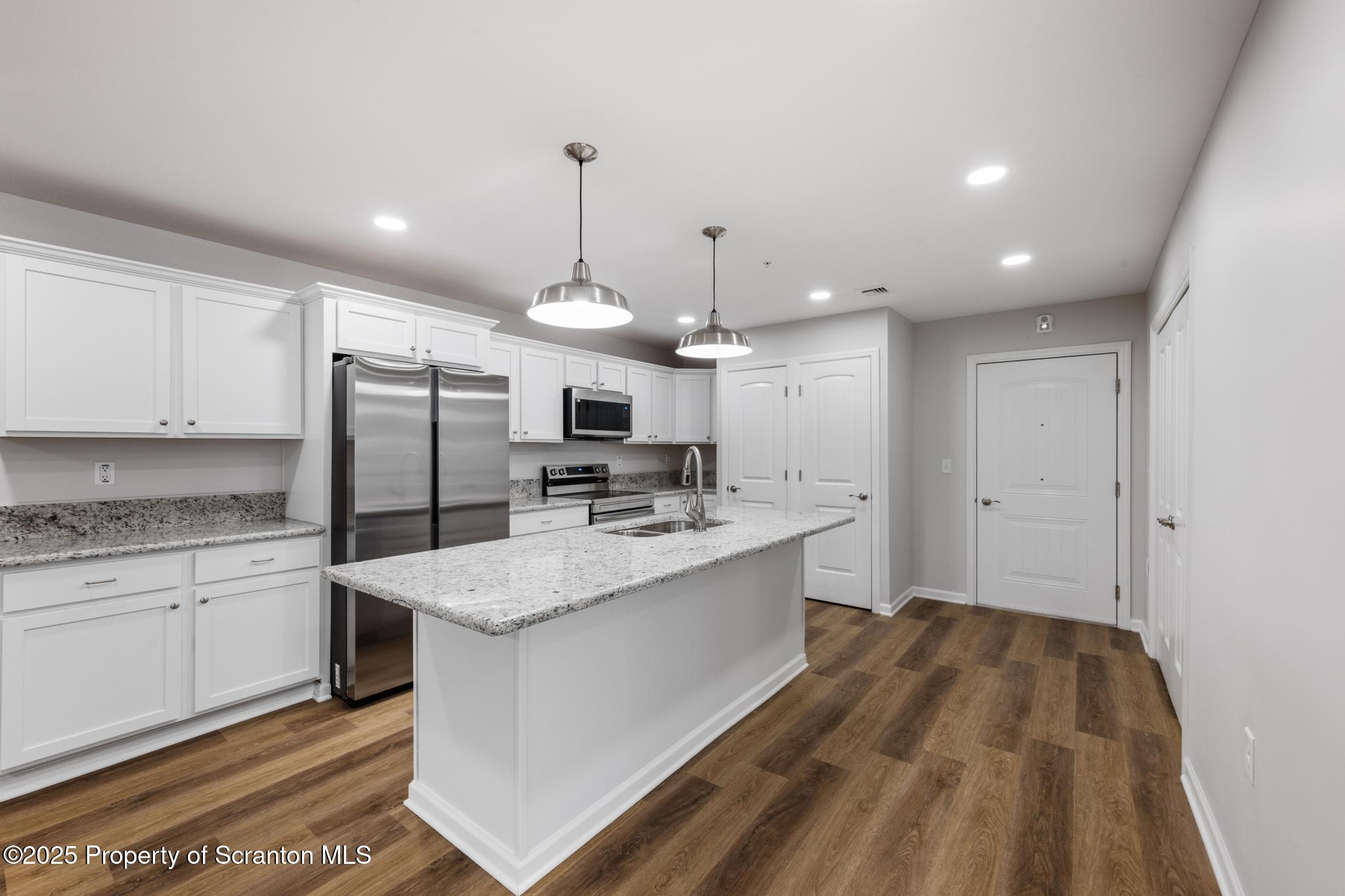 45 Zackery Way Old Forge, PA 18518 - Photo 10 of 26 a large kitchen with kitchen island a stove a sink a refrigerator and white cabinets with wooden floor