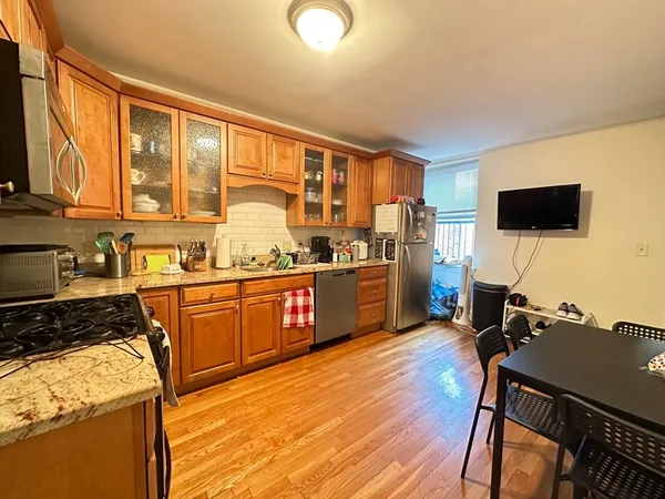 a kitchen with stainless steel appliances granite countertop a stove top oven a sink dishwasher and wooden cabinets with wooden floor