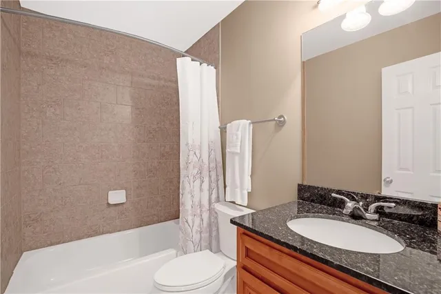 a bathroom with a granite countertop sink toilet a mirror and shower