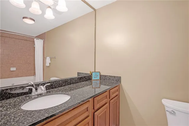 a bathroom with a granite countertop sink a mirror and a toilet