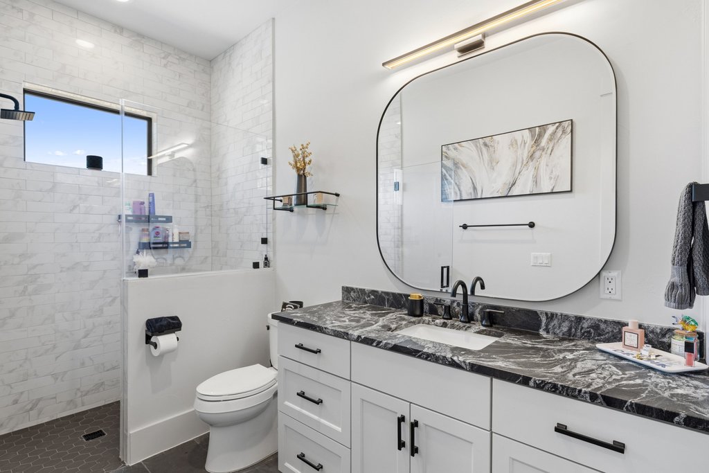 1660 Windmill Run Wimberley, TX 78676 - Photo 20 of 40 a bathroom with a granite countertop sink mirror vanity and toilet