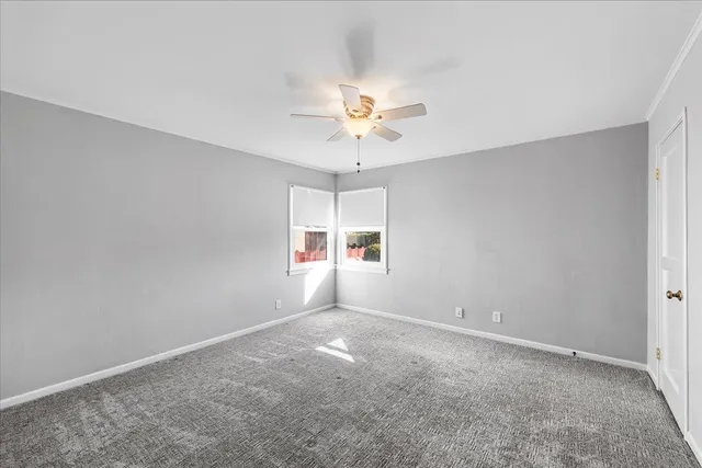 an empty room with a window and a ceiling fan