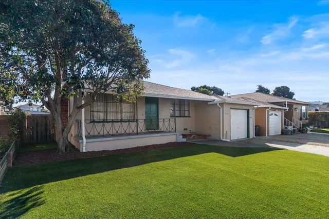 a front view of a house with a yard and trees
