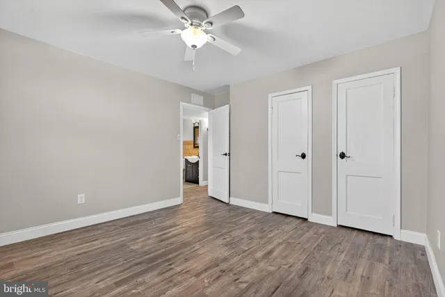an empty room with wooden floor and ceiling fan