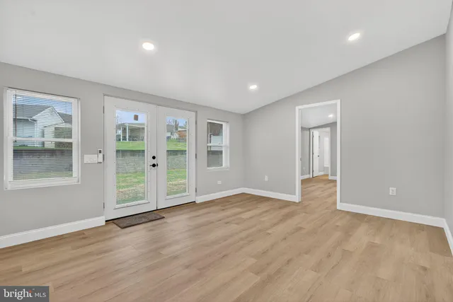 a view of an empty room with wooden floor and windows