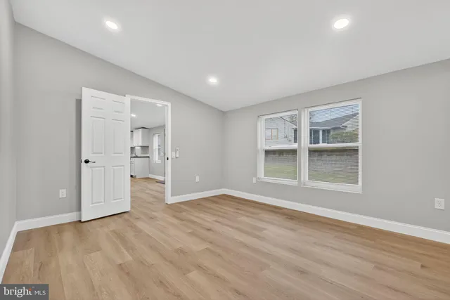 a view of empty room with wooden floor and windows