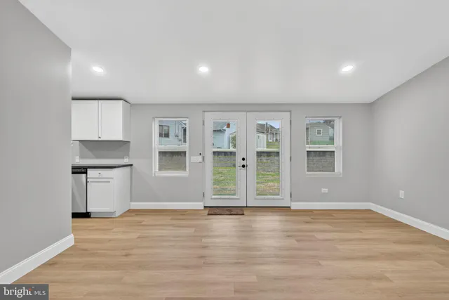 an empty room with wooden floor and windows
