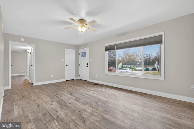 a view of an empty room with a window and wooden floor