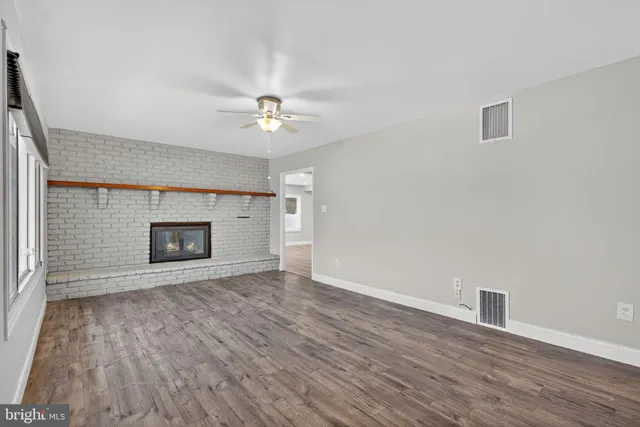 a view of empty room with wooden floor and fireplace
