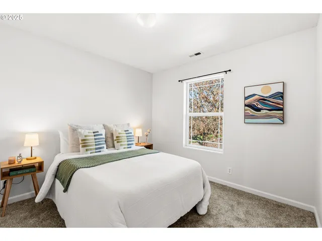 a bedroom with a bed a wall painting and a window