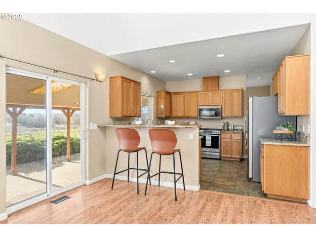 a kitchen with stainless steel appliances kitchen island granite countertop a refrigerator a stove a sink dishwasher with a dining table and chairs with wooden floor
