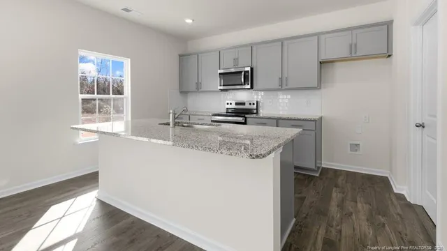 a kitchen with stainless steel appliances granite countertop a sink stove and microwave