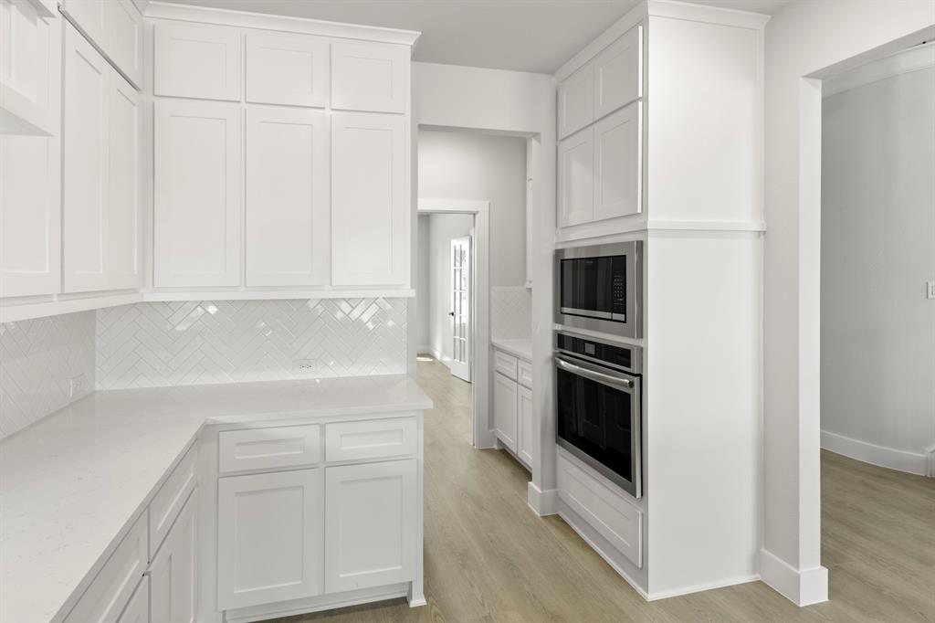 13709 Riola Drive Little Elm, TX 75068 - Photo 20 of 40 a kitchen with white cabinets and stainless steel appliances