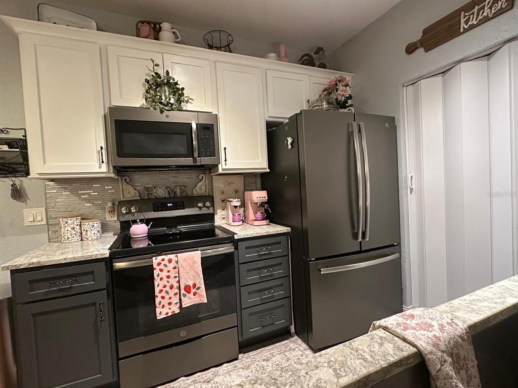 875 Grand Regency Pointe, Unit 203 Altamonte Springs, FL 32714 - Photo 4 of 17 a kitchen with stainless steel appliances kitchen island granite countertop a refrigerator stove and microwave
