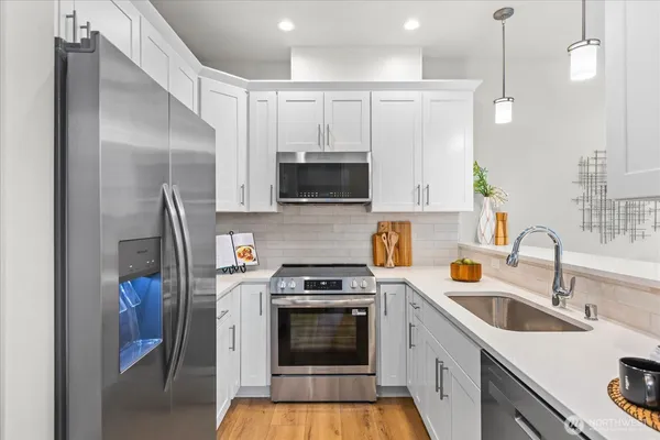 a kitchen with stainless steel appliances a stove a sink a refrigerator and a microwave