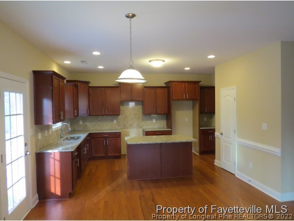 44 Golden Rod (lot 65) Cir Spring Lake Spring Lake, NC 28390 - Photo 4 of 13 a kitchen with stainless steel appliances granite countertop a refrigerator a sink dishwasher a dining table and chairs with wooden floor