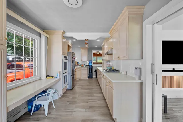 a large white kitchen with stainless steel appliances kitchen island granite countertop a large counter top and a stove top oven