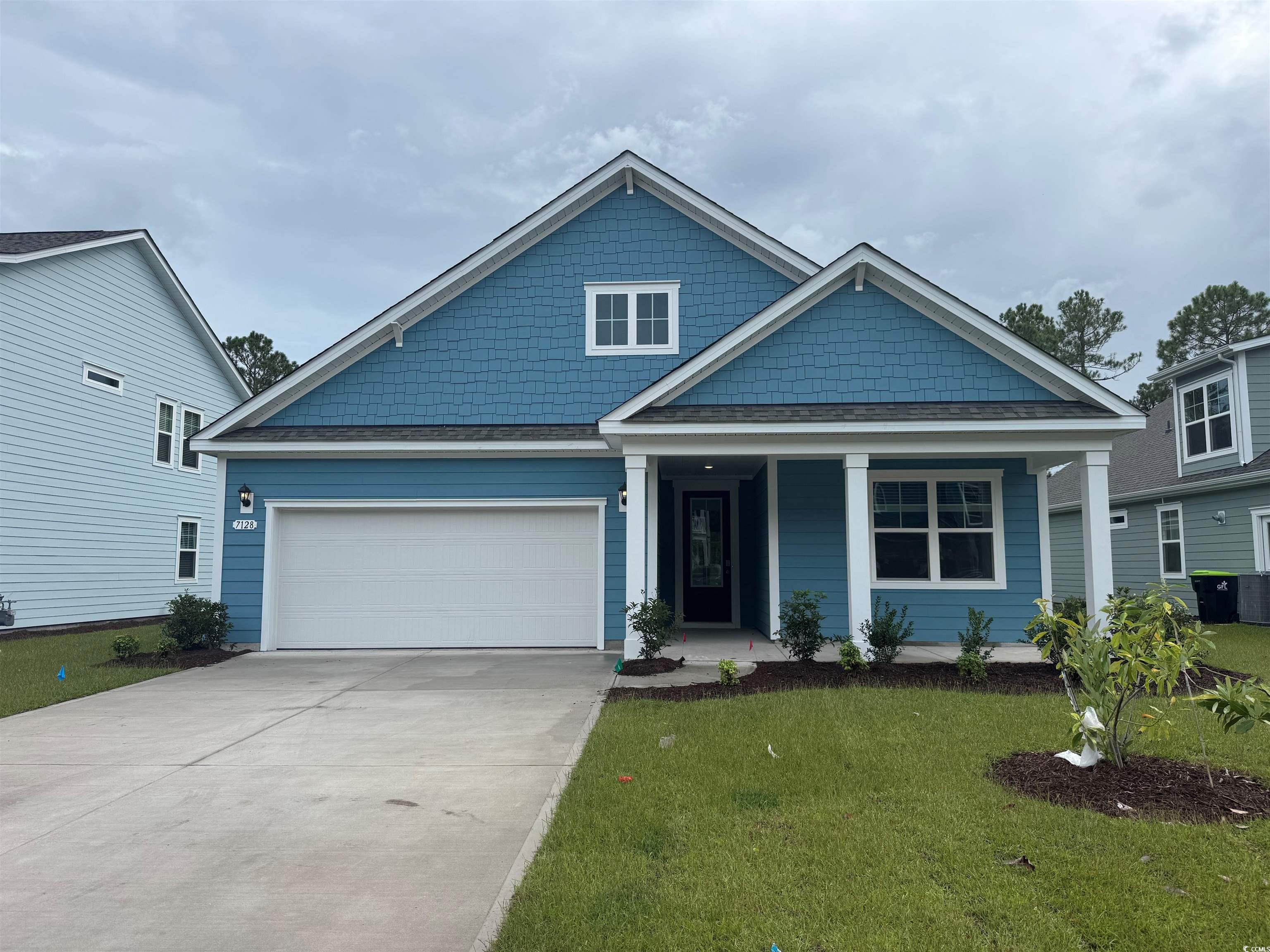 View of front of property with a front lawn, concrete driveway, roof with shingles, covered porch, and a garage