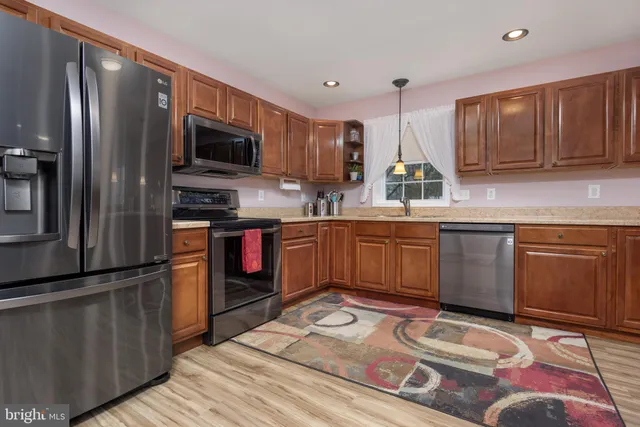 a kitchen with stainless steel appliances granite countertop a sink counter space cabinets and a wooden floor