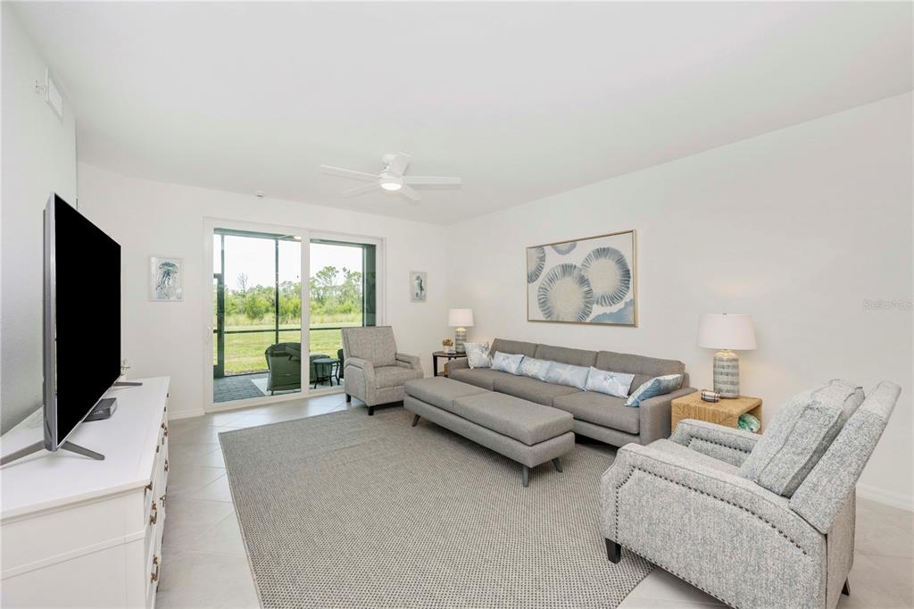 17500 Opal Sand Drive, Unit 101 Venice, FL 34293 - Photo 16 of 98 a living room with furniture large window and a flat screen tv