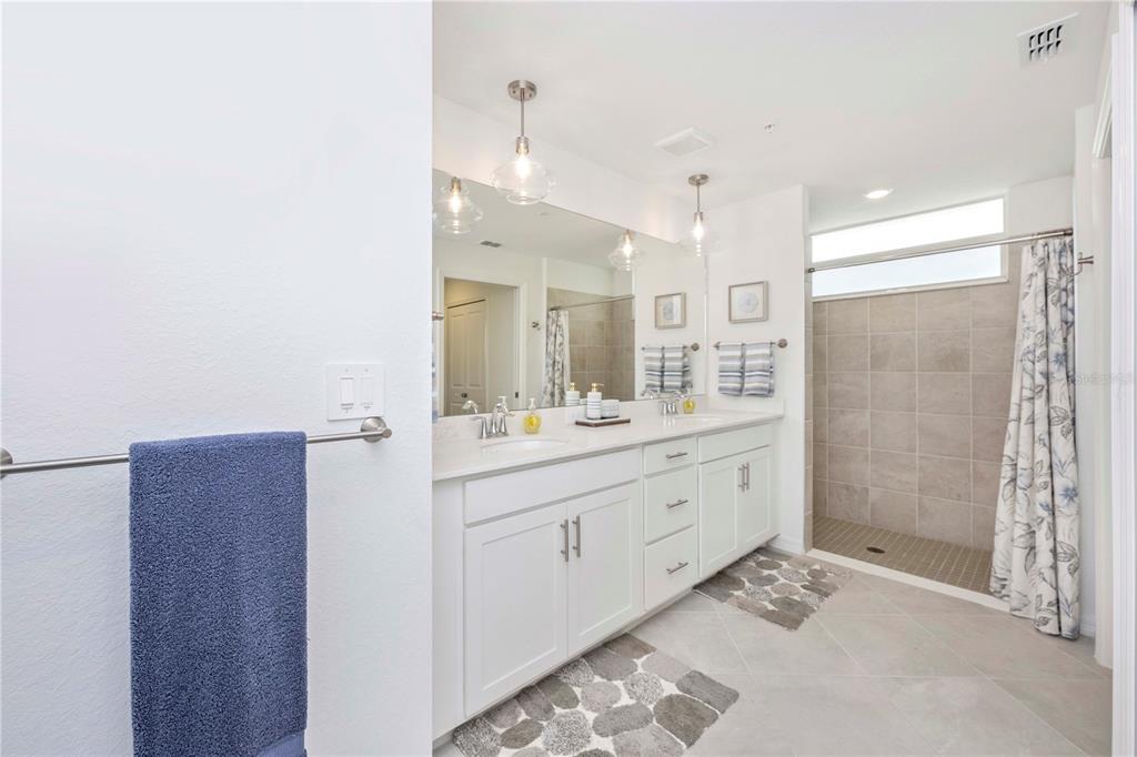 17500 Opal Sand Drive, Unit 101 Venice, FL 34293 - Photo 33 of 98 a bathroom with a double vanity sink mirror and shower